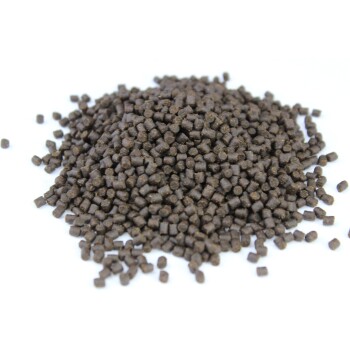 Eine Nahaufnahme eines Haufens kleiner, dunkelbrauner Haustierfutterpellets auf einem weißen Hintergrund, die ihre einheitliche Form und Textur zeigt.