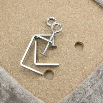 Metallmontagezubehör, einschließlich einer gebogenen Metallhalterung, Schrauben und einem Stift, der auf einer strukturierten Oberfläche mit einem weichen grauen Rand liegt.