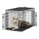 Ein glücklicher, flauschiger Hund mit einem grau-weißen Fell, der in einer schwarzen Draht-Hundekiste mit zwei offenen Türen entspannt.