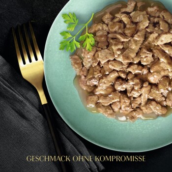 Ein grüner Teller mit feuchter, zerrissener Tiernahrung, garniert mit Petersilie, neben einer goldenen Gabel und einer schwarzen Serviette. Text: "GESCHMACK OHNE KOMPROMISSE."