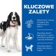 Szczęśliwy czarno-biały pies stoi obok niebieskiego panelu z zaletami: Witamina E, baranina z ryżem i wysokiej jakości białko.