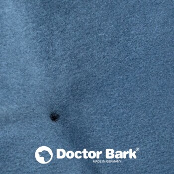 Nahaufnahme eines weichen blauen Stoffes mit einem kleinen schwarzen Punkt, mit dem Logo "Doctor Bark" und dem Text "MADE IN GERMANY."
