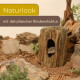 Leopardgecko lugt aus einer rindenähnlichen Höhle auf felsigem Substrat; Text: 'Naturlook' und 'mit detailreicher Rindenstruktur'