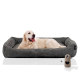 Ein Golden Retriever liegt bequem auf einem plüschigen, grauen Hundebett mit einem gerippten Design, begleitet von einem kleinen herzförmigen Schloss.