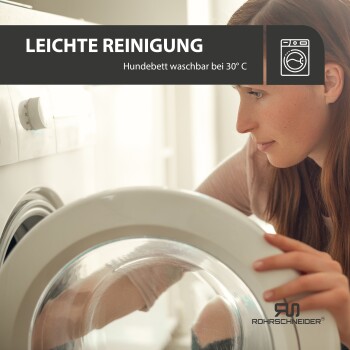 Eine Person legt ein Hundebett in eine Waschmaschine, mit dem Text 'LEICHTE REINIGUNG Hundebett waschbar bei' sichtbar darüber.