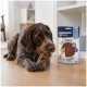 Drahthaariger brauner Hund, der an einem Leckerli kaut, neben einer Tüte mit der Aufschrift 'PREMIERE I love my dog - Fun Snack Sandwich' 70g.