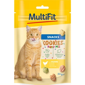A playful orange cat licks its lips in front of a colorful "MultiFit Cookies Happy Mix" snack package with chicken and catnip treats.