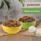 Zwei Schalen mit Haustierfutter, eine gelbe und eine grüne, gefüllt mit einer proteinreichen Mischung, die als "proteinreich" und "Reich an Huhn" gekennzeichnet ist.