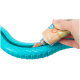 Eine Hand drückt eine Tube mit Haustierfutter in ein türkisfarbenes Gummispielzeug, das für Haustiere entworfen wurde, und zeigt die Textur und Verpackungsdetails des Futters.