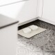 Zwei weiße Futternäpfe mit der Aufschrift "FUTTERNAPF" und "WASSERNAPF" stehen auf einer beigen Matte auf einem gemusterten Boden, unter einem Küchenschrank.