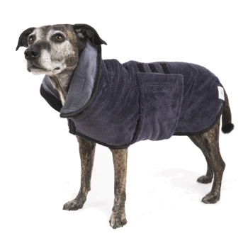 Ein mittelgroßer Hund mit gestromtem Fell trägt einen dunkelgrauen, plüschigen Haustiermantel mit großem Kragen und Klettverschlüssen.