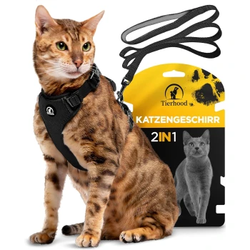 Eine Bengal-Katze, die ein schwarzes Geschirr trägt, sitzt neben einer Verpackung mit der Aufschrift "Tierhood Katzengeschirr 2IN1," die eine Katzensilhouette zeigt.