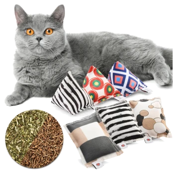 Eine graue Katze mit leuchtend orangefarbenen Augen liegt neben bunten, mit Katzenminze gefüllten Spielzeugen in verschiedenen Mustern, mit getrockneter Katzenminze darunter.