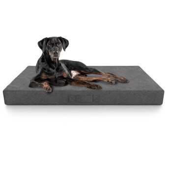 Ein schwarz-brauner Hund ruht sich bequem auf einem grauen Haustierbett aus und zeigt seine entspannte Haltung und weiche Felltextur.