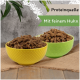 Zwei Schalen mit Haustierfutter, eine gelbe und eine grüne, gefüllt mit einer stückigen Fleischmischung, beschriftet mit "Proteinquelle" und "Mit feinem Huhn."