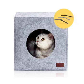 Ein graues Filz-Katzenhaus mit einer runden Öffnung, in dem eine neugierige Katze mit gelben Augen herausspäht. Das Markenlogo "piupet" ist an der Seite sichtbar.