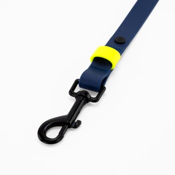 Eine blaue Hundeleine mit gelben Akzenten und schwarzen Clips, flach auf einem weißen Hintergrund ausgelegt.