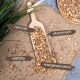 Eine Holzschaufel gefüllt mit bunten Samen und Nüssen auf Jute, mit Etiketten: 'nahrhaft', 'vitaminreich', 'vielfältig', 'energiespendend'.