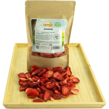 Getrocknete Erdbeer-Haustierleckerlis in einer braunen Papiertüte mit der Aufschrift "GETZOO ERDBEEREN," mit einem Haufen Leckerlis auf einem Holztablett.