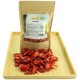 Getrocknete Erdbeer-Haustierleckerlis in einer braunen Papiertüte mit der Aufschrift "GETZOO ERDBEEREN," mit einem Haufen Leckerlis auf einem Holztablett.