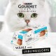 Eine weiße Katze mit grünen Augen neben einer Purina Gourmet Revelations Katzenfutterverpackung, die mit "Mousse mit Thunfisch" beschriftet ist.