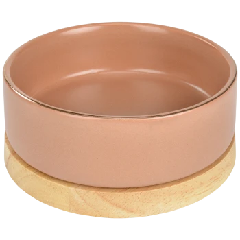 Keramischer Haustierfutterschüssel in sanftem Rosa, der auf einer natürlichen Holzunterlage ruht.