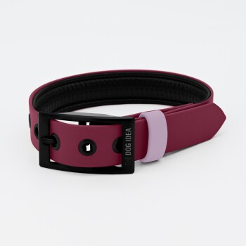 Ein kastanienbraunes Hundehalsband mit einer schwarzen Schnalle und einem lavendelfarbenen Akzent, mit dem Text 'THE DOG IDEA' auf der Schnalle.