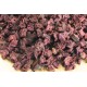 Getrocknete Hibiskusblütenblätter in verschiedenen Rottönen und Lila, verstreut auf einer hellen Holzoberfläche.