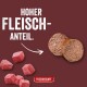 Rohes Rindfleischwürfel und zwei Fleischpastetenrunden auf dunkelrotem Hintergrund; Text 'HOHER FLEISCHANTEIL.' und Marke 'FLEISCHESLUST'.