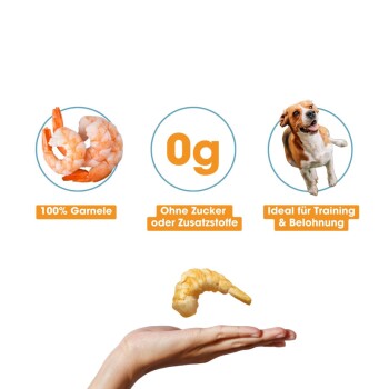 Hand hält einen Garnelen-Leckerbissen mit der Aufschrift "100% Garnele", "0g", "Ohne Zucker oder Zusatzstoffe" und "Ideal für Training & Belohnung."