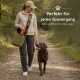Frau in kariertem Hemd und Jeans sitzt auf Gras mit einem Deutsch Kurzhaar Hund in einem bewaldeten Gebiet.