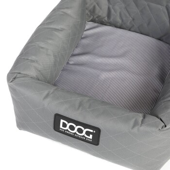 Graues, gestepptes Hundebett mit gestreiftem Innenraum, ausgestattet mit einem schwarzen DOOG-Logoetikett, das "DOG OWNERS OUTDOOR GEAR" liest.