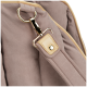 Close-up of a beige pet carrier strap with gold metal clasp and ring on soft fabric background.