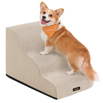 Corgi mit orangefarbenem Halstuch mit der Aufschrift 'Feandrea' steigt eine graue, strukturierte Haustiertreppe neben einem beigefarbenen Sofa hinauf.