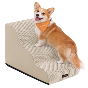 Corgi mit orangefarbenem Halstuch mit der Aufschrift 'Feandrea' steigt eine graue, strukturierte Haustiertreppe neben einem beigefarbenen Sofa hinauf.