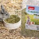 Ein grauer Hase frisst Heu aus einer weißen Schüssel, neben einem Sack PANTO Premiumhay mit Kaninchen und einem Meerschweinchen auf dem Etikett.