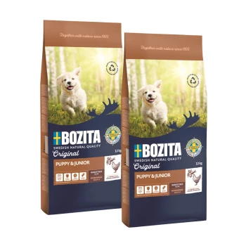 Zwei Säcke Bozita Hundefutter mit der Aufschrift "Original Puppy & Junior", jeweils 12 kg, mit einem glücklichen Welpen vor einem grünen Hintergrund.