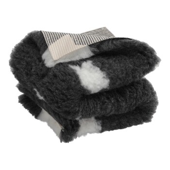 Gefaltete schwarz-weiße flauschige Haustierdecke mit sichtbarem gestreiftem beige-schwarzem Etikett oben.