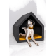 Ein schwarz-weißer Hund entspannt sich in einem stilvollen grauen Hundehäuschen mit einem goldenen Kissen und sieht zufrieden und entspannt aus.