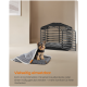 Kleiner Hund sitzt auf einer grauen Haustierdecke mit einem grauen Haustierkäfig und Kissen im Hintergrund; Deutscher Text über Vielseitigkeit.