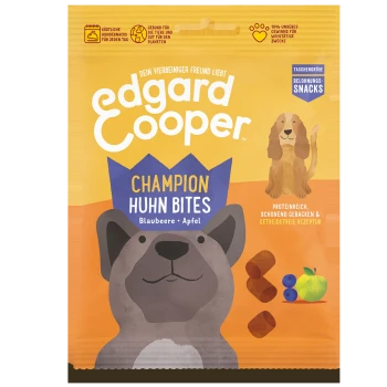 Edgard Cooper Champion Huhn Bites Hundeleckerlis Verpackung mit einer Cartoon-Hund, Heidelbeeren und Apfelillustrationen, mit Text auf Deutsch.