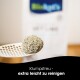 Eine Hand hält eine Schaufel mit klumpendem Katzenstreu, im Hintergrund eine verschwommene Tüte mit dem Text "Klumpstreu - extra leicht zu reinigen."