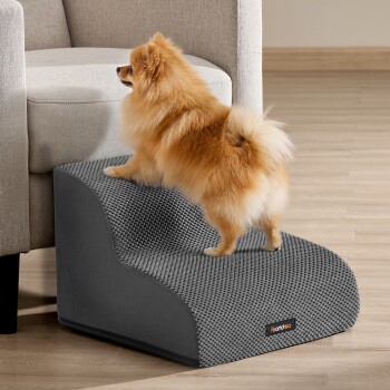 Pomeranian auf einer grauen strukturierten Haustierrampe neben dem Sofa, Produktetikett 'Feandrea'.