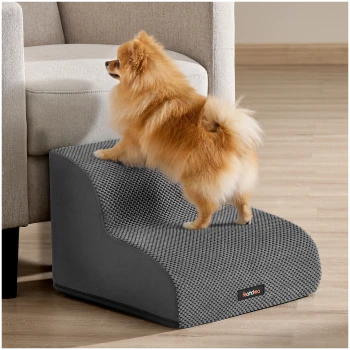 Pomeranian auf einer grauen strukturierten Haustierrampe neben dem Sofa, Produktetikett 'Feandrea'.