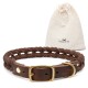 Ein geflochtenes braunes Leder-Hundehalsband mit einer goldenen Schnalle, neben einem kleinen beigen Beutel mit Kordelzug, der mit "FREUDENTIER" beschriftet ist.