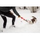 Eine Person in einer schwarzen Daunenjacke und Handschuhen spielt im tiefen Schnee Tauziehen mit einem weiß-braunen Hund.