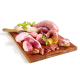 Ein Holzschneidebrett hält rohes Huhn, Schweinefleisch und Innereien, garniert mit Kräutern und einer kleinen Schüssel Öl.