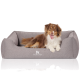 Ein gemütliches graues Hundebett mit einem weißen Logo mit der Aufschrift "KNUFFELWUFF," auf dem ein glücklicher Hund bequem liegt.