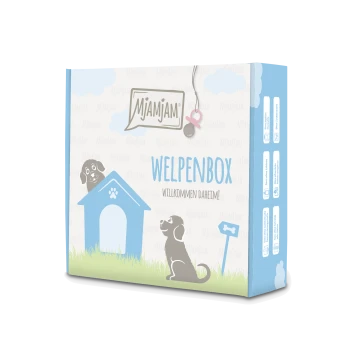 Emballage de Mjamjam Welpenbox présentant une maison de chien bleue, des illustrations de chiens joueurs, et le texte "WELPENBOX WILKOMMEN DAHEIM!"