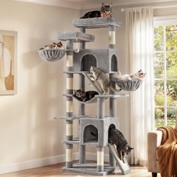 Hoher grauer plüschiger mehrstufiger Kratzbaum in einem Wohnzimmer mit sieben Katzen auf Plattformen, Hängematten, Rampen und Häuschen.